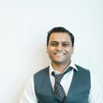 Portrait of a cheerful man in business attire posing confidently indoors.